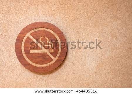No smoking sign are made of wood on the wall.