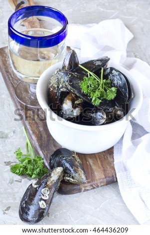 Sailors mussels in White bowl on s?ratched grey cement background with glass of white wine