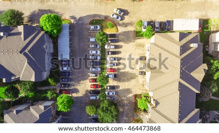 Aerial view of apartment garage with full of covered parking, cars and green trees of multi-floor residential building in early morning. Urban infrastructure and transportation concept. Panorama view.
