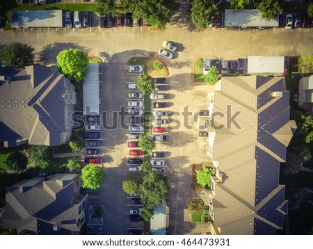 Aerial view of apartment garage with full of covered parking, cars and green trees of multi-floor residential building in early morning. Urban infrastructure and transportation concept. Vintage filter