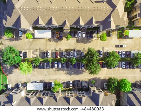Aerial view of apartment garage with full of covered parking, cars and green trees of multi-floor residential buildings in Houston, TX in early morning. Urban infrastructure and transportation concept