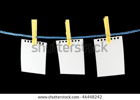 Blank pieces of paper hang on clothesline isolated on black