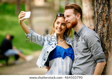 Beautiful couple in love taking slefies outdoors in park