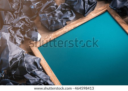 empty chalkboard with free copy space on rustic wooden plank and black crumpled trash paper balls creativity ideas concept