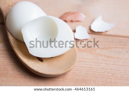 Boiled egg peeling on wooden spoon