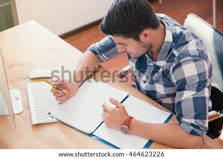 Businessman in casual cloth reading and signing document in office