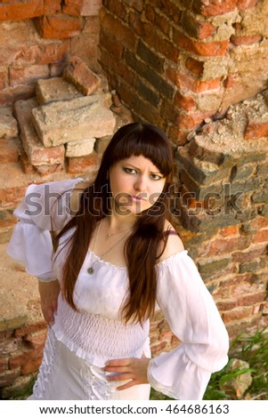 girl in a ball gown among the ruins of antiquity. white clothes on a young girl on brick wall background