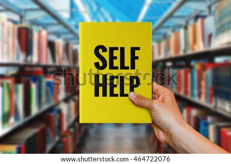 A hand holding 'Self-Help' book. Royalty-Free Stock Photo #464722076