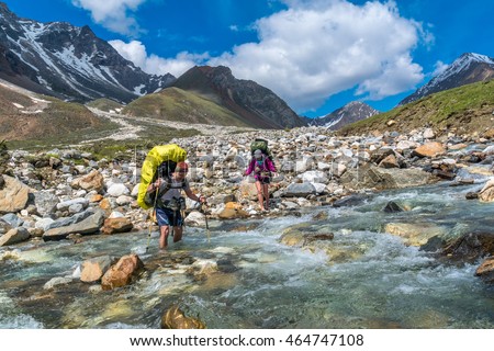 Two tourists crossing the mountainous river Ekhe-Ger, Siberia Royalty-Free Stock Photo #464747108