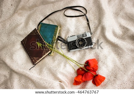 Vintage old photo photocamera for film near red poppies and notepads