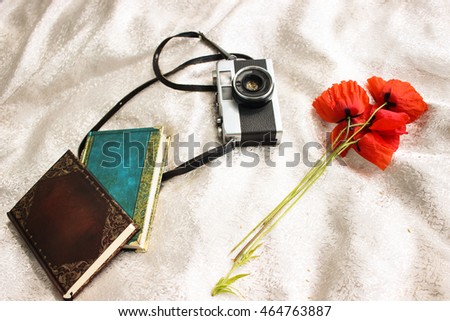 Vintage old photo photocamera for film near red poppies and notepads