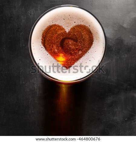 loving beer, heart symbol on foam in glass on black table, view from above Royalty-Free Stock Photo #464800676