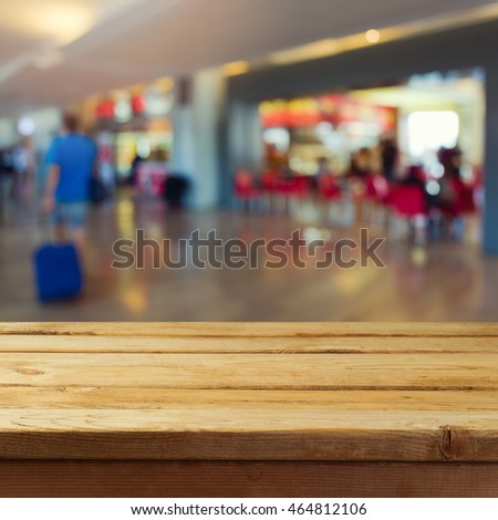 Empty wooden deck table over airport interior bokeh background