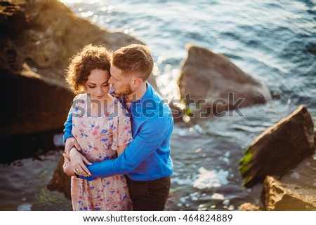 A picture of a couple standing in the sea water in the lights of sunset