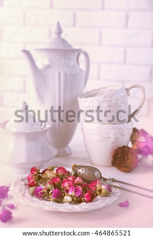 Tea set and tea rose flowers on table on brick wall background
