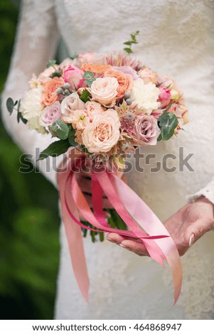 bouquet from roses in the bride's hands. Pink tapes