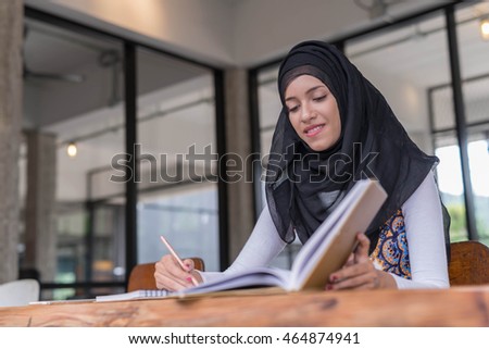 Happy indian woman working and writing notebook paper