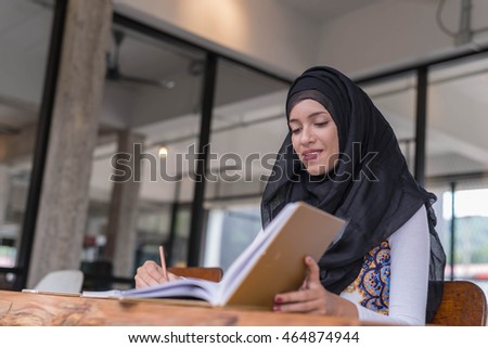 Happy indian woman working and writing notebook paper