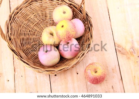 Apples in basket on brown wooden background.