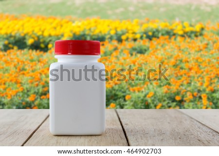 Blank medicine bottle isolated on wood table with garden background
