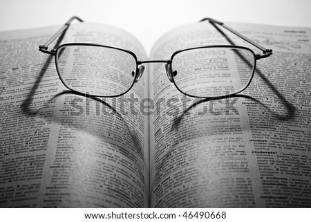 Monochrome photo of open book with glasses in dark