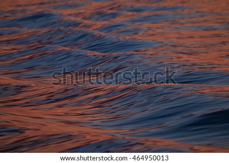 Abstract of sea waves reflecting beautiful red light of setting sun
