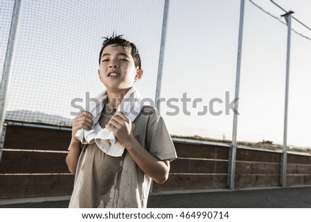 A confident boy with a towel around his neck after a hard practice looks ready for more. Royalty-Free Stock Photo #464990714