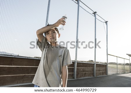 A boy tired out after practice wipes his sweaty head. Royalty-Free Stock Photo #464990729