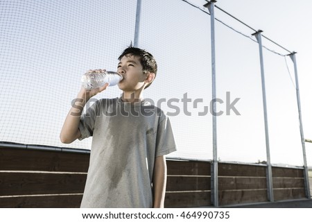 A young boy drinks water after a hard day of practice. Royalty-Free Stock Photo #464990735