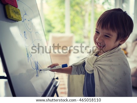 Little kid painting and drawing on board canvas at home