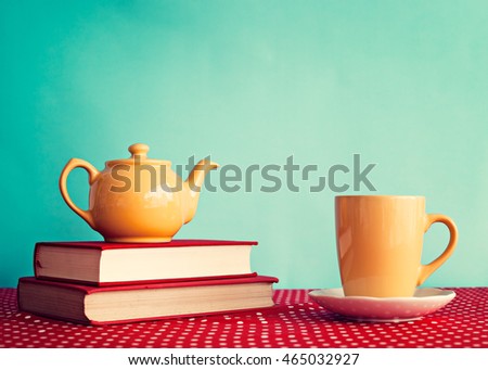 Yellow teapot over books and yellow mug