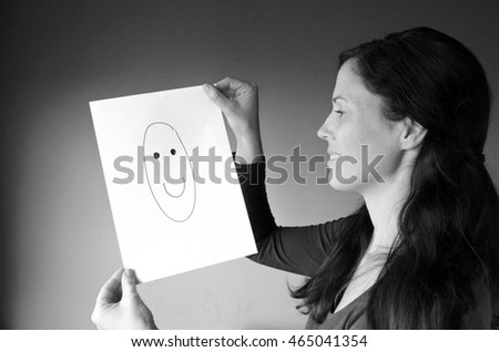 Young woman looks at a drawing with a happy face. Woman lifestyle concept. copy space (BW)