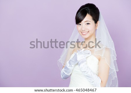 attractive asian woman wearing wedding dress isolated on purple background