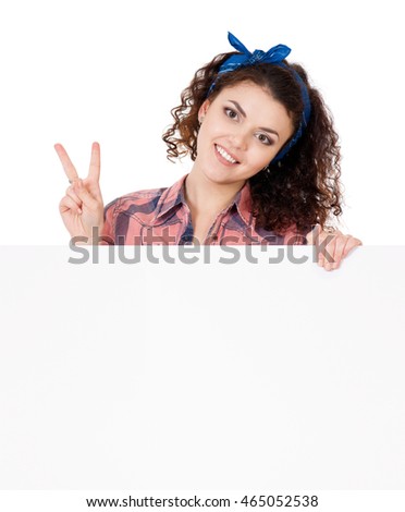 Portrait of a happy young casual woman holding a blank signboard showing victory sign, isolated on white background