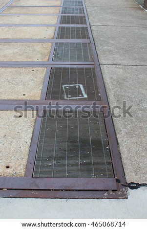 Perspective photograph of rusty industrial sidewalk grates with a spray painted rectangle