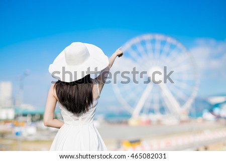 young woman wear dress and behind you with ferris wheel 