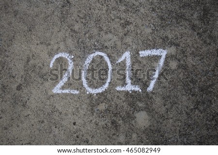 Writing the word "2017" with chalk on the street floor.