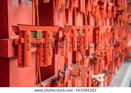 wish messagein japan language  that Prayers writen on small red wooden Torii Gates at Fushimi Inari Shrine in Kyoto, Japan. Selective focus on traditional japanese writing.