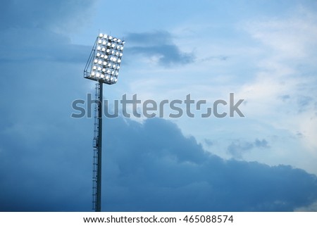 Mast with spotlights illuminate on stadium and raincloud background Royalty-Free Stock Photo #465088574