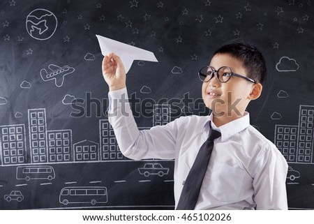 Portrait of a cute schoolboy playing a paper airplane in the classroom