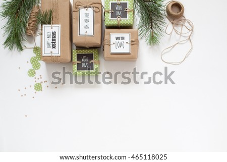 Gifts wrapped in brown craft paper. The branches of the Christmas tree. Gifts tied with jute rope.