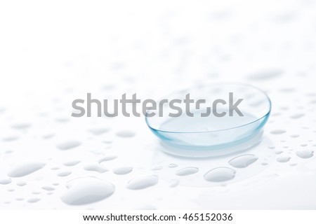 Contact lens close-up on white background with water drops.