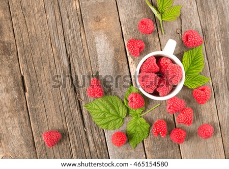 Old wooden background scattered red raspberry. In the circle berry.