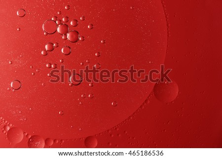 Abstract of red oil drops on water. Light is in the upper left corner