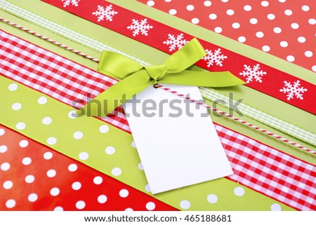 Modern Christmas holiday greeting background with bright red and avocado green gift wrapping with multiple ribbons and gift tag.