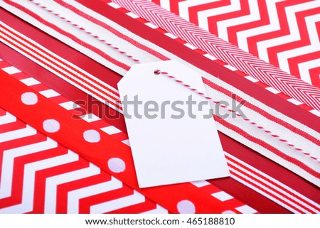Modern holiday greeting background with close up of festive red and white gift wrapping with multiple ribbons on red and white chevron stripe paper. 