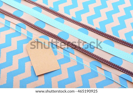 Modern holiday greeting background with close up of vintage gift wrapping with multiple ribbons and gift tag on aqua chevron striped natural brown paper. 