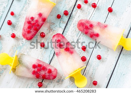Red currant popsicles on wooden background, top view.