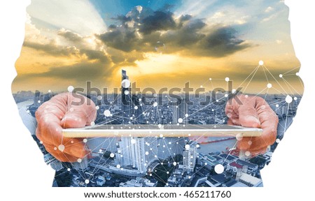 Concept of smart phone or tablet connecting network to urban life. Double layers view of city scape and indoor hand image.
