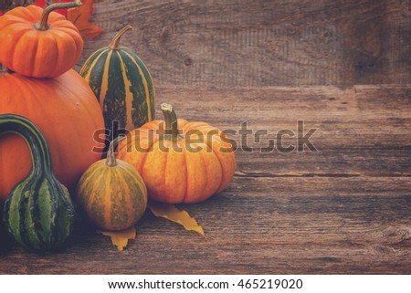 pile of orange and green pumpkins on wooden table with copy space, retro toned
